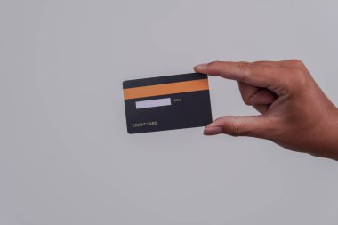 Person's hand showing the back of a credit card or debit card with black color over isolated white background.