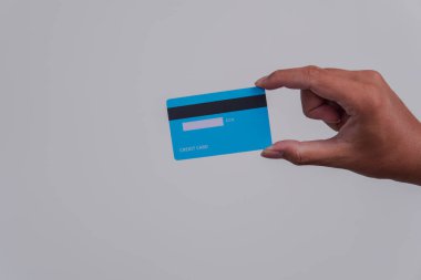 Person's hand showing the back of a credit card or debit card with blue color over isolated white background.