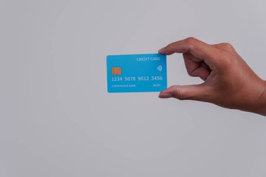 Person's hand showing the front of a credit card or debit card with blue color over isolated white background.