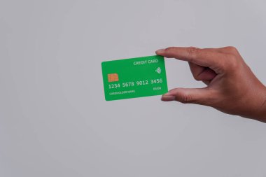 Person's hand showing the front of a credit card or debit card with green color over isolated white background.