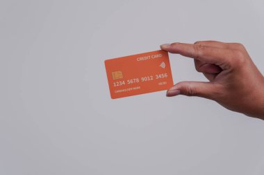 Person's hand showing the front of a credit card or debit card with orange color over isolated white background.