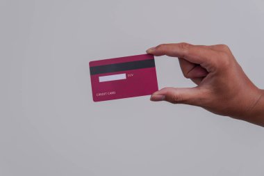 Person's hand showing the back of a credit card or debit card with red color over isolated white background.