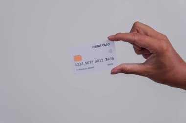 Person's hand showing the front of a credit card or debit card with white color over isolated white background.