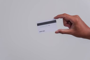 Person's hand showing the back of a credit card or debit card with white color over isolated white background.