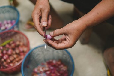 Person is holding a knife to peeling onion skin and cut the onions.