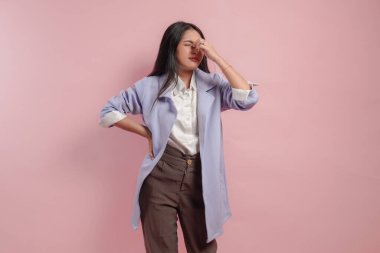 Şiddetli baş ağrısı çeken stresli genç Asyalı kadın, tapınaklara ellerini bastırıyor, acını dindirmek için gözlerini kapatıyor çaresiz yüz ifadesiyle..