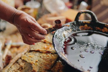 Close-up of a canting tool used in hand batik making with a pan of malam wax.