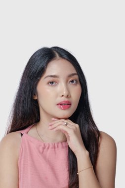 Güzel makyajlı zarif bir Asyalı kadın beyaz arka planda izole edilmiş şık bir poz veriyor..