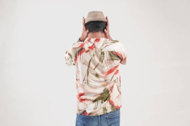 Hawaii tişörtü giymiş genç bir Asyalı 'nın arka portresi. Kafasını tutuyor. Stresli hissediyor..