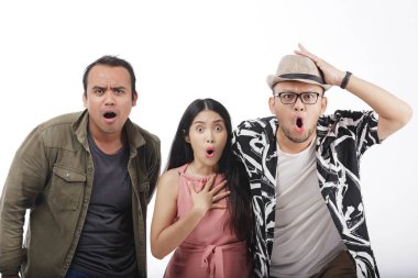 Üç Asyalı kameraya şok olmuş bir ifadeyle bakıyor, beyaz arka planla izole edilmiş..