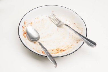 Masada çatal ve kaşıkla kirli tabak. Fotoğraf yemekten sonra tabağın nasıl temizleneceği konsepti için kullanılabilir.