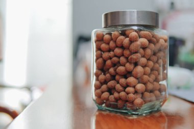 Çiğ soyulmuş ve cam kavanozdaki fıstıklar masada atıştırmalık gibi bulanık arka planda..