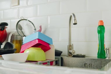 Mutfakta bulaşık takımlarıyla dolu metal lavabo ve yeşil bulaşık deterjanı. Bulaşık yıkama kavramı.