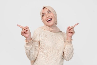 Tesettürlü genç Asyalı Müslüman kadın beyaz arka planla izole edilmiş fotokopi odasını işaret ediyor. Ramazan kavramı.