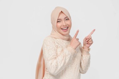 Tesettürlü genç Asyalı Müslüman kadın beyaz arka planla izole edilmiş fotokopi odasını işaret ediyor. Ramazan kavramı.