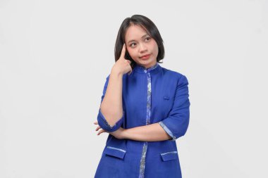 Thoughtful Asian customer service woman in blue uniform looking serious while thinking of idea, isolated by white background.