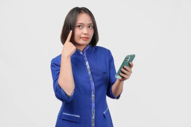 Ciddi Asyalı müşteri hizmetlerinden mavi üniformalı bir kadın elinde akıllı telefon, beyaz arka plan tarafından izole edilmiş..