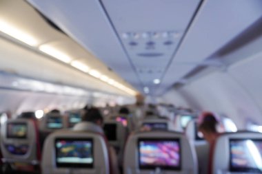 Person is pointing at a map on a screen behind passenger seat inside an airplane.
