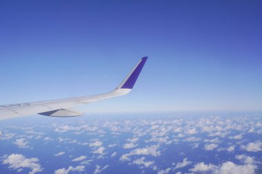 Uçuş sırasında bulutların üstünde uçak kanadı, uçak penceresinden manzara.