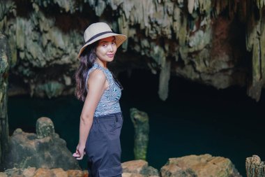 Smiling young Asian woman enjoying holiday and scenery at Rangko Cave, Labuan Bajo, Indonesia.