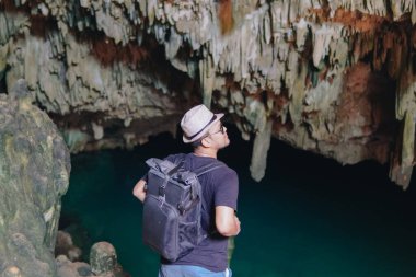 Back view of a young Asian man enjoying holiday and scenery at Rangko Cave, Labuan Bajo, Indonesia.