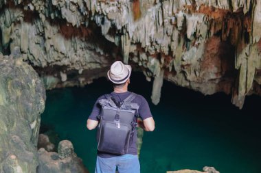 Back view of a young Asian man enjoying holiday and scenery at Rangko Cave, Labuan Bajo, Indonesia.