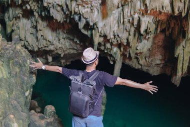 Excited young Asian man enjoying holiday and scenery at Rangko Cave, Labuan Bajo, Indonesia.