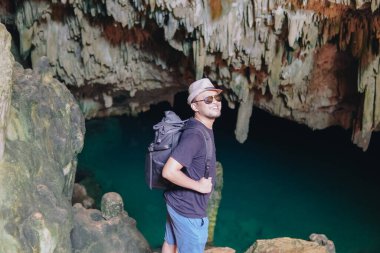 Smiling young Asian man enjoying holiday and scenery at Rangko Cave, Labuan Bajo, Indonesia.