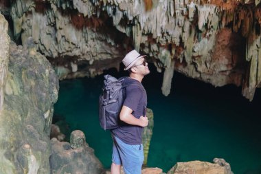 Smiling young Asian man enjoying holiday and scenery at Rangko Cave, Labuan Bajo, Indonesia.