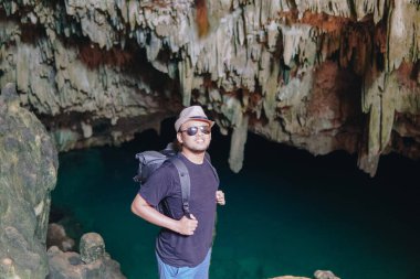 Smiling young Asian man enjoying holiday and scenery at Rangko Cave, Labuan Bajo, Indonesia.