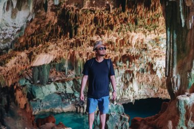 Smiling young Asian man enjoying holiday and scenery at Rangko Cave, Labuan Bajo, Indonesia.