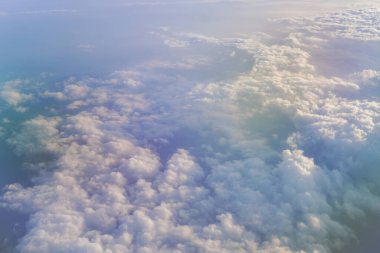 Bulutlu mavi gökyüzünün hava görüntüsü, uçuşun ortasında uçak penceresinden manzara.