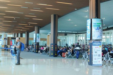 Interior of Labuan Bajo departure arrival airport lounge with people walking around.