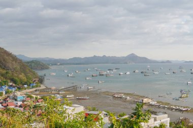 Scenery of Labuan Bajo harbor with boat sailing in the ocean and the cityscape, Indonesia tourist destination.