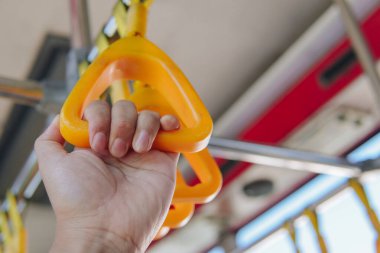 Close up of a passenger's hand holding handrails in a public transport for travel or commuting.