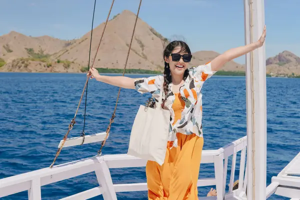 Teknede durup Labuan Bajo 'da tatilin tadını çıkarırken kameraya gülümseyen heyecanlı Asyalı genç kadın..