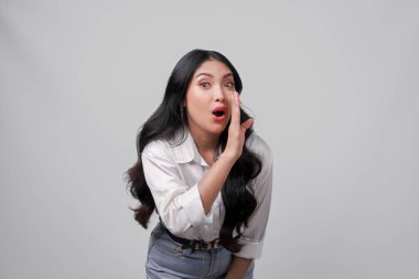 Güzel genç Asyalı kadın bağırıyor ve çığlık atıyor. Elleri ağzında, beyaz arka planda soyutlanmış..