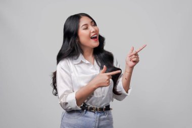 Beyaz gömlekli neşeli genç Asyalı kadın yanındaki fotokopi odasını işaret ediyor, beyaz arka planla izole edilmiş..