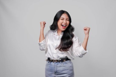 Beyaz gömlekli heyecanlı genç Asyalı kadın mutlu ve başarılı bir ifadeyle, beyaz arka planla izole edilmiş..