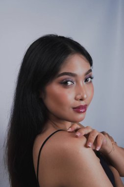 Kameraya poz veren genç, güzel bir Asyalı kadın, mor göz farı ve kırmızı dudaklarıyla. Güzellik konsepti.