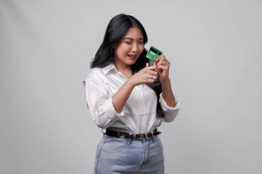 Ağlayan genç Asyalı kadın elinde makasla kredi kartı ya da banka kartını kesiyor, beyaz arka planla izole edilmiş..