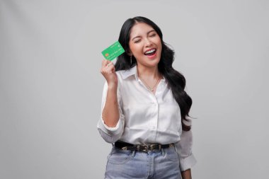 Beyaz gömlek giyen neşeli genç Asyalı kadın, beyaz arka planla izole edilmiş bir kredi kartı sunuyor..
