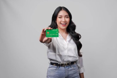 Beyaz gömlek giyen neşeli genç Asyalı kadın, beyaz arka planla izole edilmiş bir kredi kartı sunuyor..