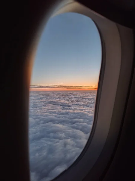 Sunset in the clouds seen through the window of an airplane.