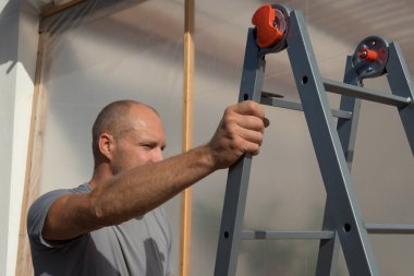 İnşaat işçisi iş yerinde merdiveni tırmanır..