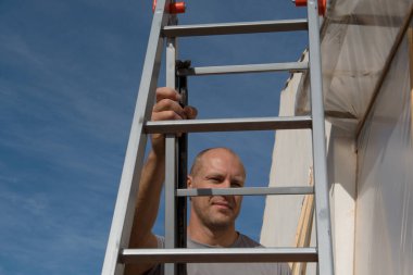 İnşaat işçisi iş yerinde merdiveni tırmanır..