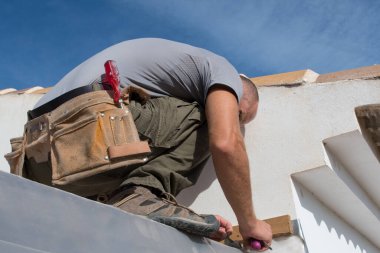 İnşaat işçisi bir evin çatısını tamir ediyor.