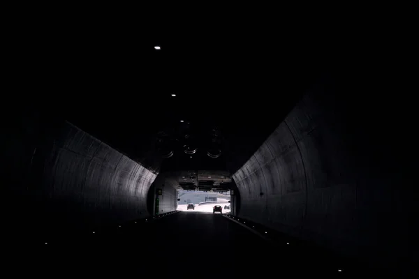 Tunnel with light at the end of it. Car is driving down the road in the tunnel. Traffic infrastructure, tunnel architecture, light effect.