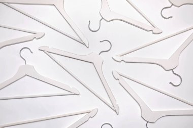 Pattern of empty white hangers flat lay on white background. Abstract coat hanger design set. Concept of shopping, household accessory.