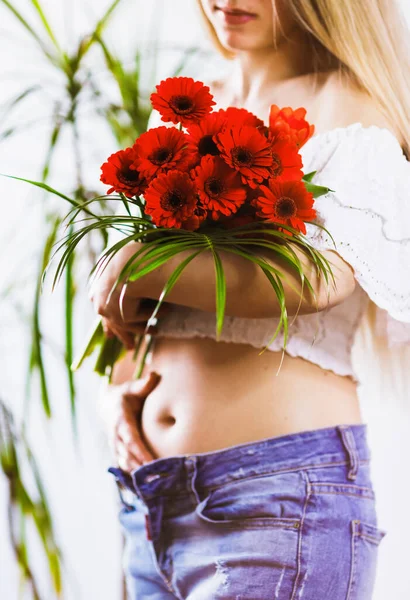 Close-up of a woman at first month of pregnancy. The blurry girl and flowers in focus.